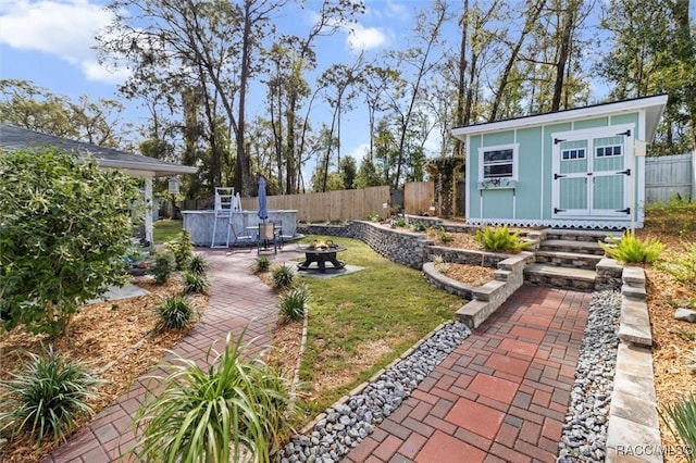 view of yard featuring an outbuilding, an outdoor fire pit, a patio area, and a fenced backyard