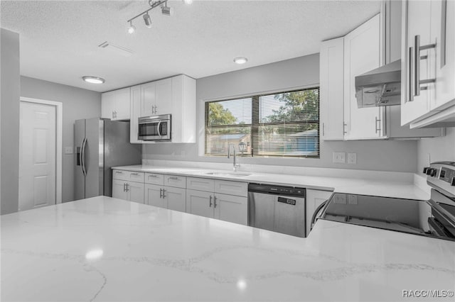 kitchen with sink, wall chimney range hood, white cabinets, and appliances with stainless steel finishes