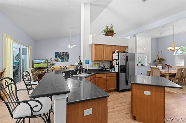 5705 N Bedstrow Blvd, Beverly Hills, FL 34465 - kitchen with stainless steel refrigerator with ice dispenser, a kitchen bar, brown cabinets, light wood-style flooring, and lofted ceiling