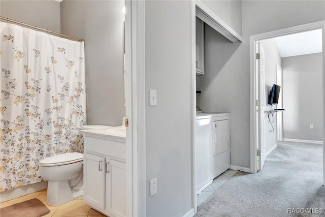 bathroom featuring toilet, vanity, tile patterned floors, and washing machine and dryer