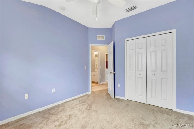 unfurnished bedroom featuring ceiling fan, a closet, light carpet, and vaulted ceiling