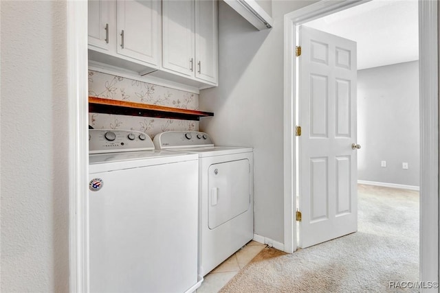 clothes washing area with washing machine and dryer, light colored carpet, and cabinets