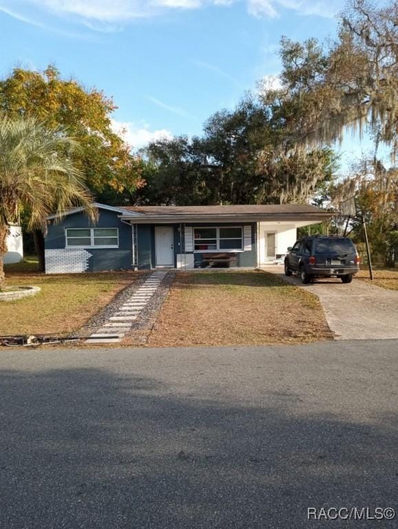 ranch-style house featuring a carport, a front lawn, and concrete driveway