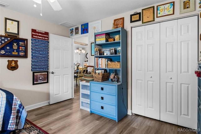 9973 N Chelic Dr, Citrus Springs, FL 34434 - bedroom featuring wood finished floors, a closet, baseboards, a ceiling fan, and a chandelier