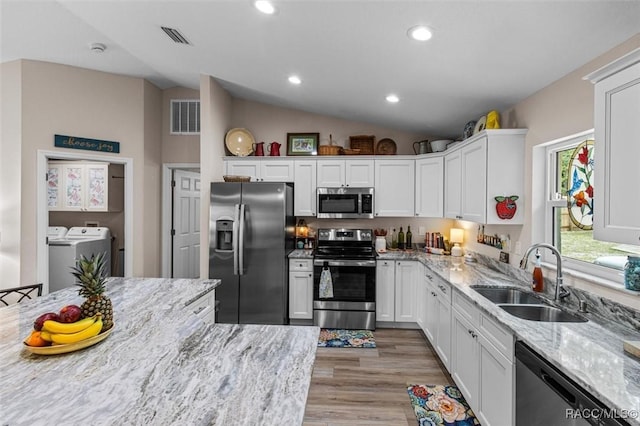 9973 N Chelic Dr, Citrus Springs, FL 34434 - kitchen featuring appliances with stainless steel finishes, independent washer and dryer, a sink, vaulted ceiling, and white cabinets