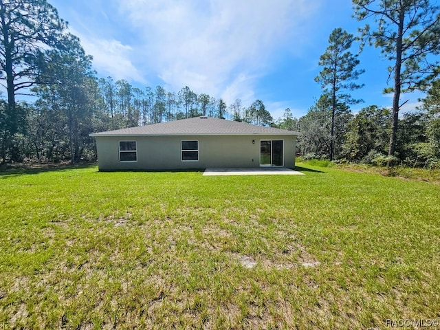 back of property with a lawn and a patio