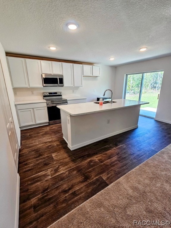 kitchen with appliances with stainless steel finishes, dark hardwood / wood-style floors, white cabinetry, and sink