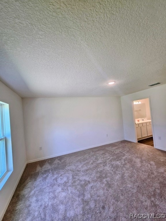 empty room with carpet flooring and a textured ceiling