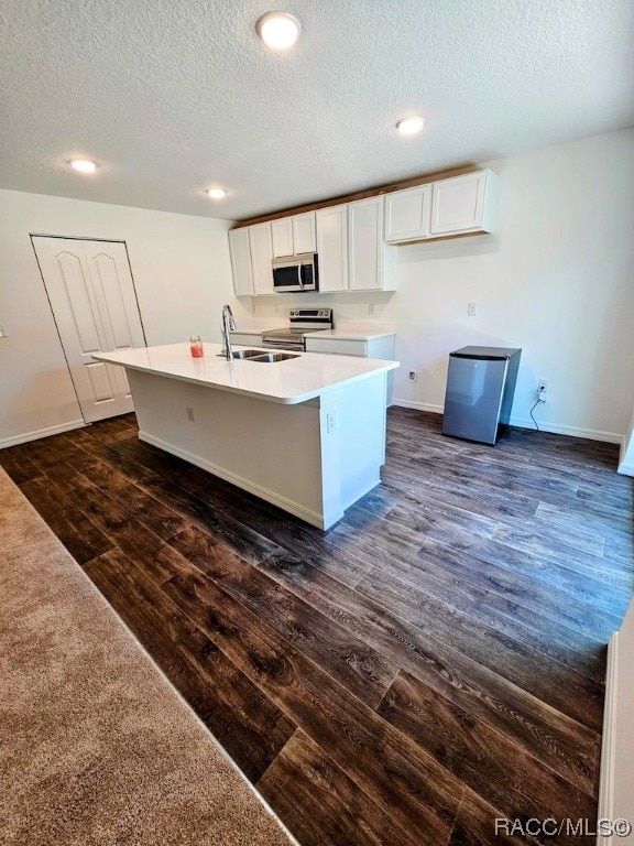 kitchen featuring white cabinets, an island with sink, dark wood-type flooring, and appliances with stainless steel finishes