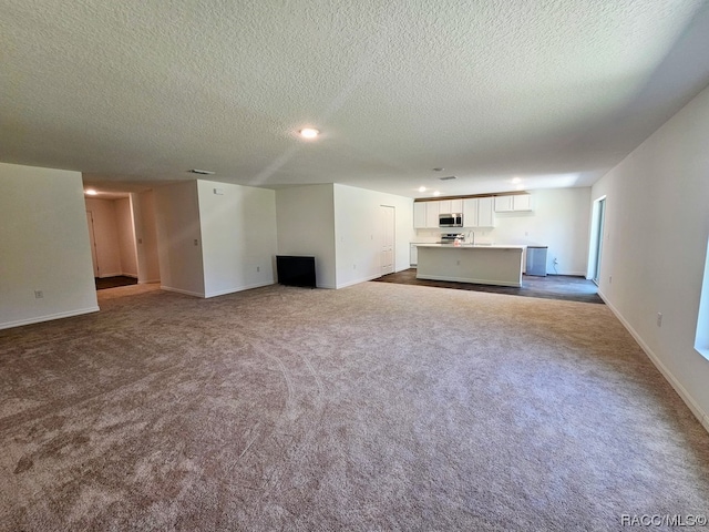 unfurnished living room featuring carpet flooring and a textured ceiling