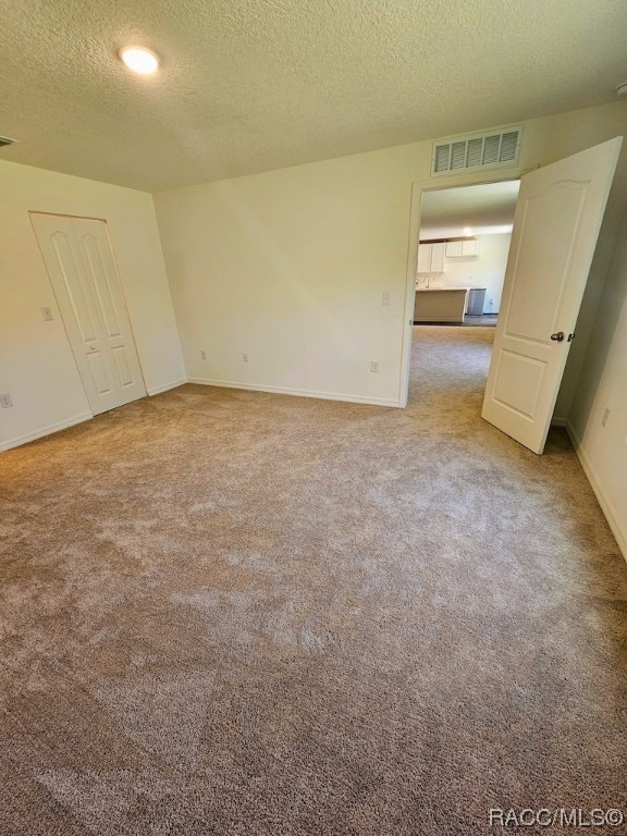 carpeted empty room featuring a textured ceiling