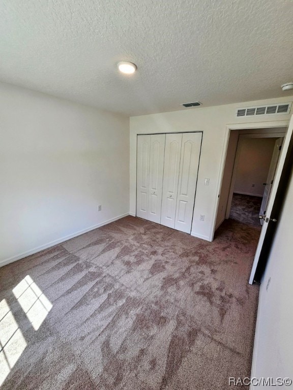 unfurnished bedroom featuring carpet flooring, a textured ceiling, and a closet