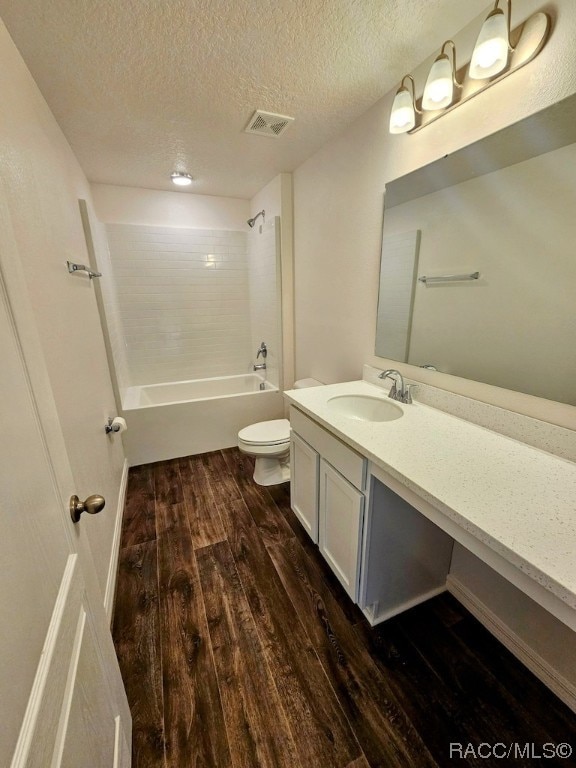 full bathroom featuring tiled shower / bath combo, wood-type flooring, a textured ceiling, toilet, and vanity