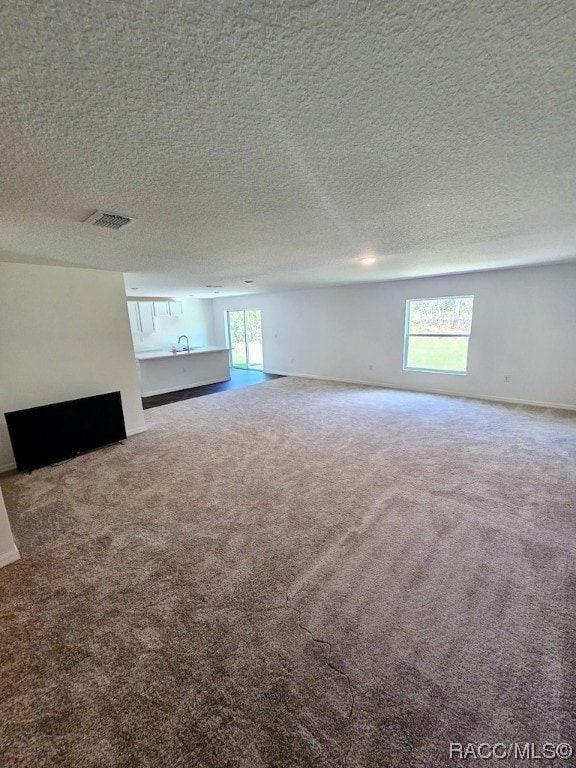 unfurnished living room featuring carpet and a textured ceiling