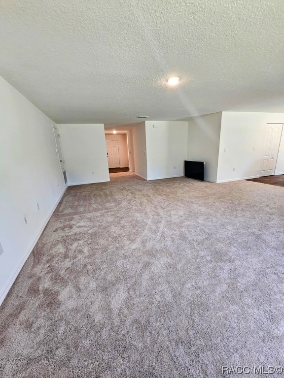 unfurnished living room featuring carpet and a textured ceiling