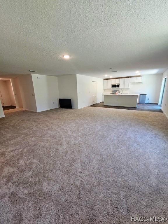 unfurnished living room featuring a textured ceiling and carpet floors