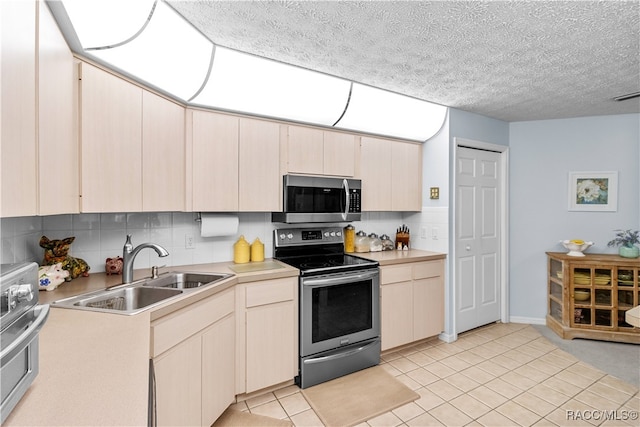 kitchen with sink, stainless steel appliances, a textured ceiling, decorative backsplash, and light tile patterned flooring