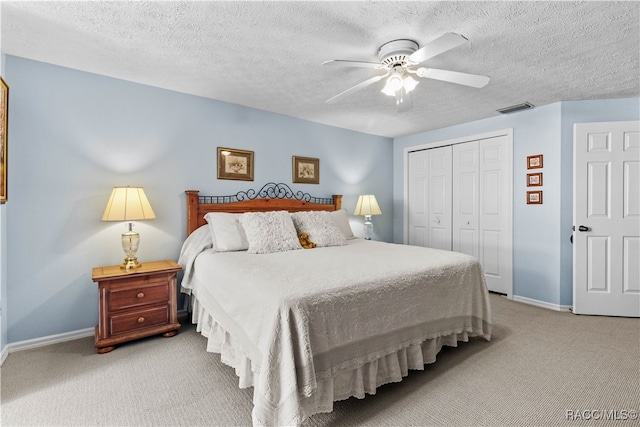 bedroom featuring ceiling fan, a closet, light colored carpet, and a textured ceiling