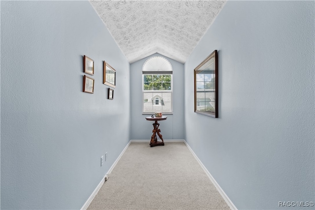 hallway featuring lofted ceiling and carpet floors