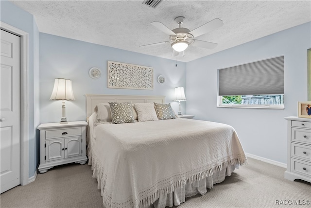 bedroom with a textured ceiling, light colored carpet, and ceiling fan