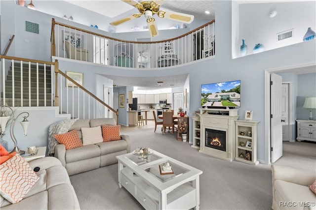 carpeted living room with a towering ceiling and ceiling fan