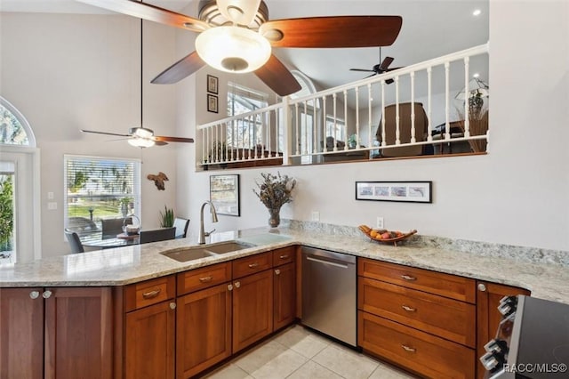 kitchen featuring sink, stove, stainless steel dishwasher, light stone counters, and kitchen peninsula