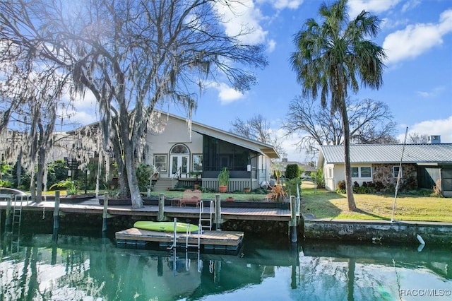 rear view of house with a yard, a sunroom, and a water view