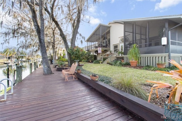 deck featuring a lawn, a sunroom, and a water view