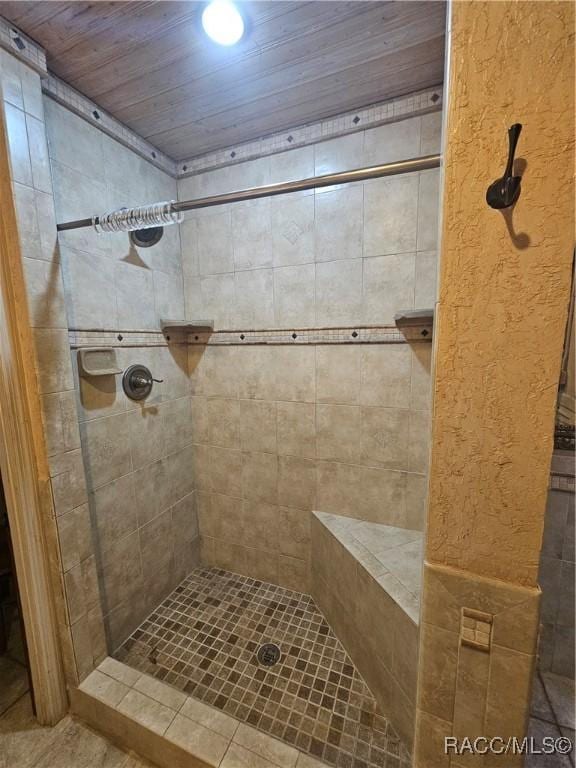 bathroom featuring a tile shower and wood ceiling