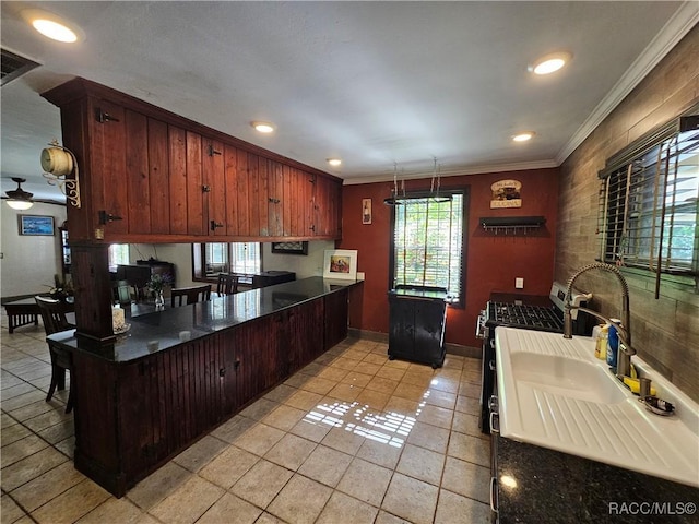 kitchen with gas range, ceiling fan, kitchen peninsula, crown molding, and light tile patterned floors