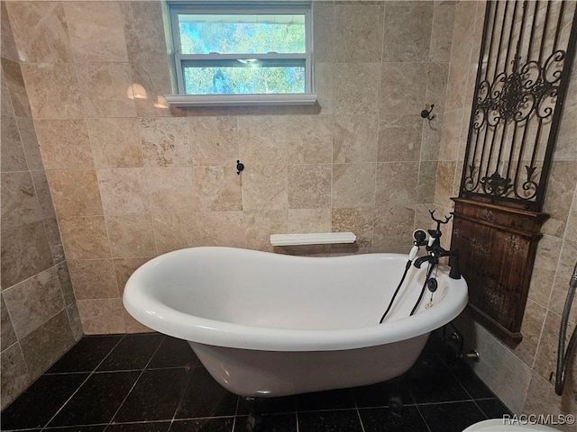 bathroom featuring tile patterned floors, a bathtub, and tile walls