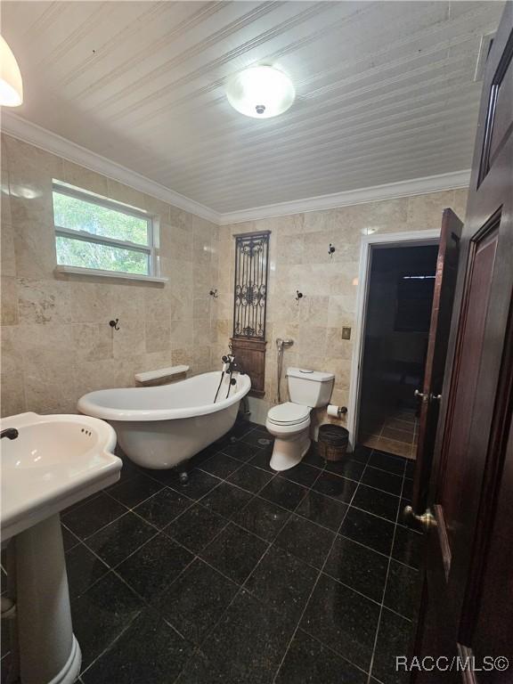 bathroom with crown molding, a bathtub, tile walls, and toilet