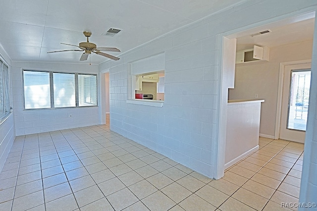 unfurnished room with a wealth of natural light, ceiling fan, and light tile patterned flooring