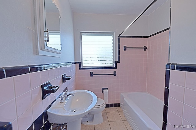 full bathroom featuring tile patterned floors, sink, tiled shower / bath, toilet, and tile walls