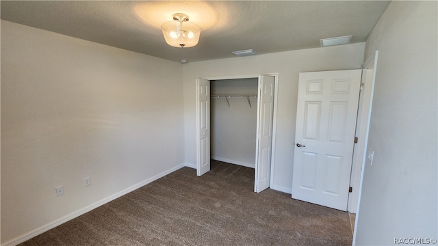 unfurnished bedroom featuring dark carpet and a closet