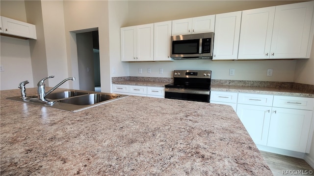 kitchen featuring wood-type flooring, sink, white cabinetry, and stainless steel appliances