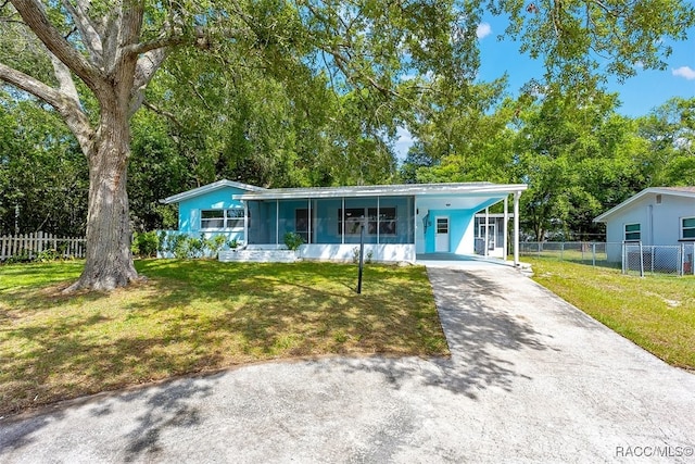 7 N Adams St, Beverly Hills, FL 34465 - view of front facade with asphalt driveway, an attached carport, a sunroom, and view of scattered trees