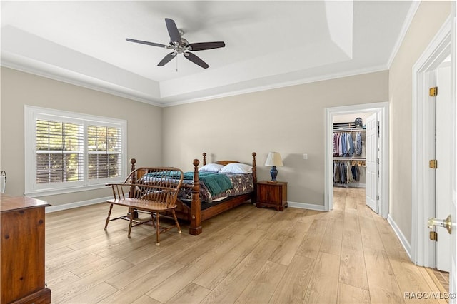 1200 N Annapolis Ave, Hernando, FL 34442 - bedroom with a tray ceiling, light wood-style flooring, crown molding, a walk in closet, and a ceiling fan