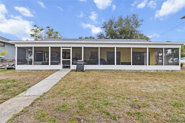 rear view of house with a sunroom and a yard