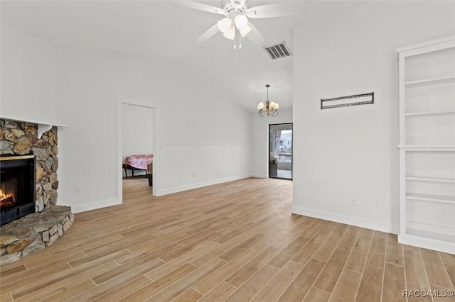 unfurnished living room featuring lofted ceiling, built in features, a fireplace, light hardwood / wood-style floors, and ceiling fan with notable chandelier