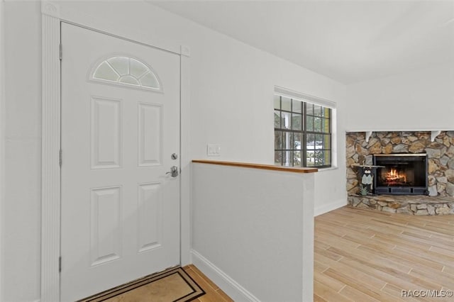 foyer featuring a stone fireplace and wood-type flooring