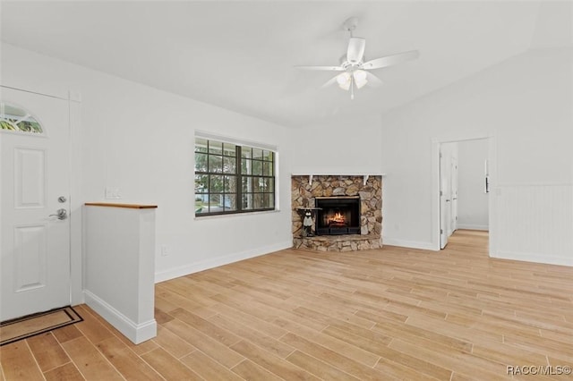 unfurnished living room with a stone fireplace, ceiling fan, and light wood-type flooring