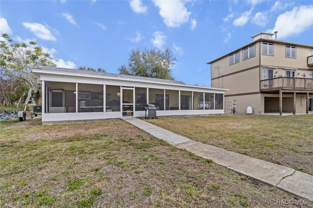 rear view of house featuring a sunroom and a lawn