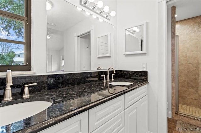 bathroom featuring a shower with door and vanity