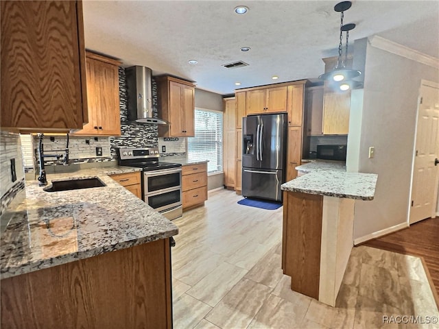 kitchen featuring light stone countertops, appliances with stainless steel finishes, wall chimney exhaust hood, and sink