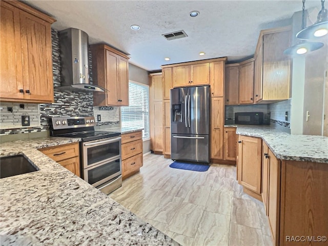 kitchen with wall chimney exhaust hood, light stone countertops, decorative light fixtures, and appliances with stainless steel finishes