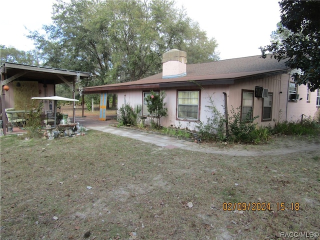 rear view of property featuring a lawn and a carport