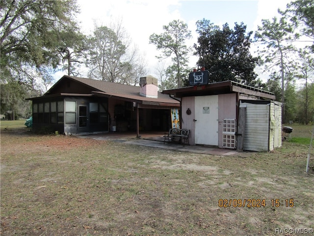 back of house with a lawn, a patio area, and a sunroom