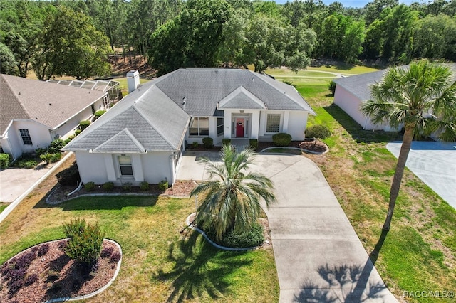 view of front of property with concrete driveway, a shingled roof, a front lawn, and stucco siding