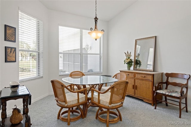 dining space featuring baseboards, light colored carpet, and vaulted ceiling